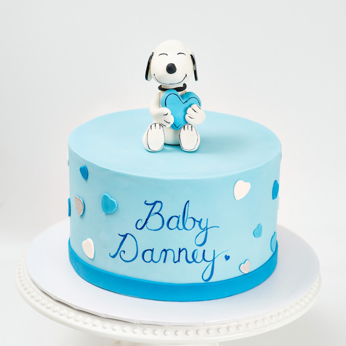 Blaue Tauftorte mit dem Namen des Babys und kleinen Herzen, süße Hund Figur aus Fondant