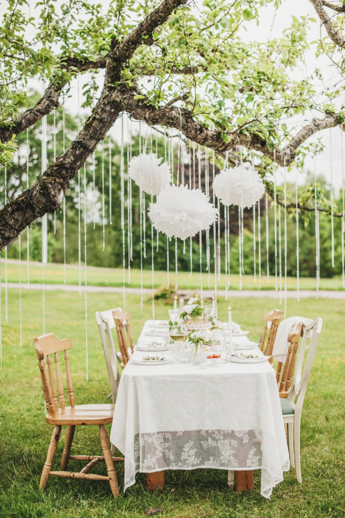 weiße Pompons, die über den Tisch hängen, alles für die Hochzeit, ein schöner Tisch