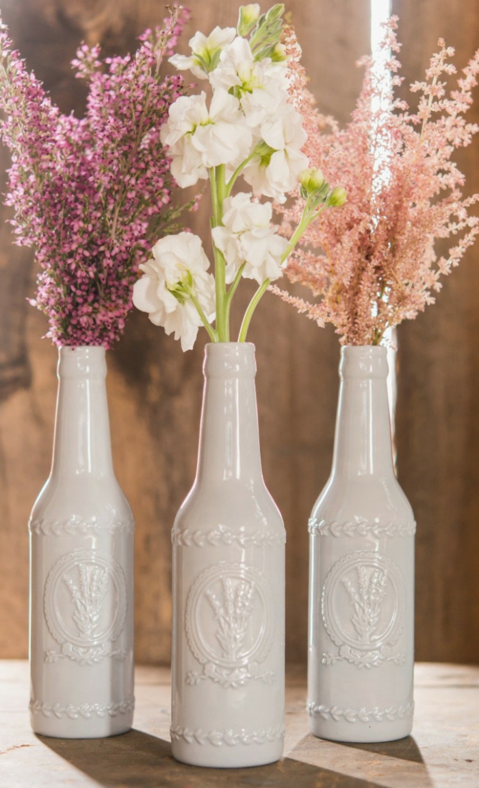 Vasen aus Bierflaschen, mit weißen Farbe bedeckt, voller Frühlingsblumen, alles für die Hochzeit