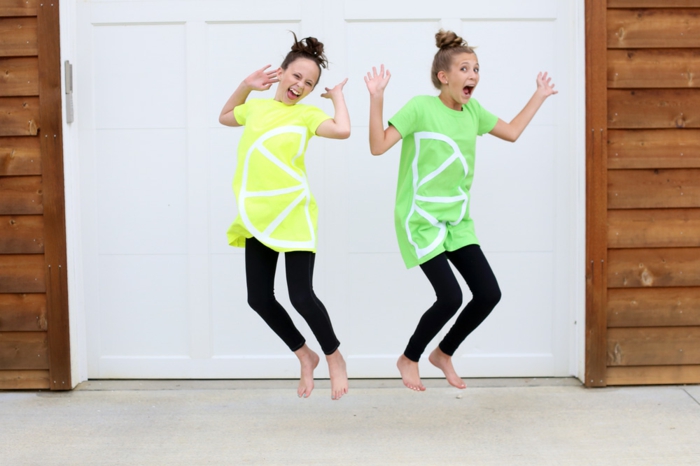 zwei Freundinnen, die springen mit grünen und gelben Blusen wie Zitrone und Limette, Halloween Verkleidung