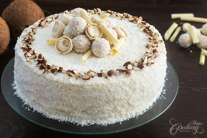 Raffaello Torte mit Pralinen geschmückt, mit zerkleinerte Mandeln umrandet, mit Kokosraspeln bedeckt