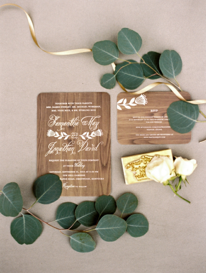 graviertes Holz als Einladungskarten, weiße Buchstaben und eine weiße Blume, Einladungskarten selber basteln
