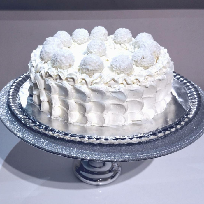 eine weiße Torte, bildschöne Dekoration von weißer Creme und Raffaello Pralinen, Raffaello Rezept