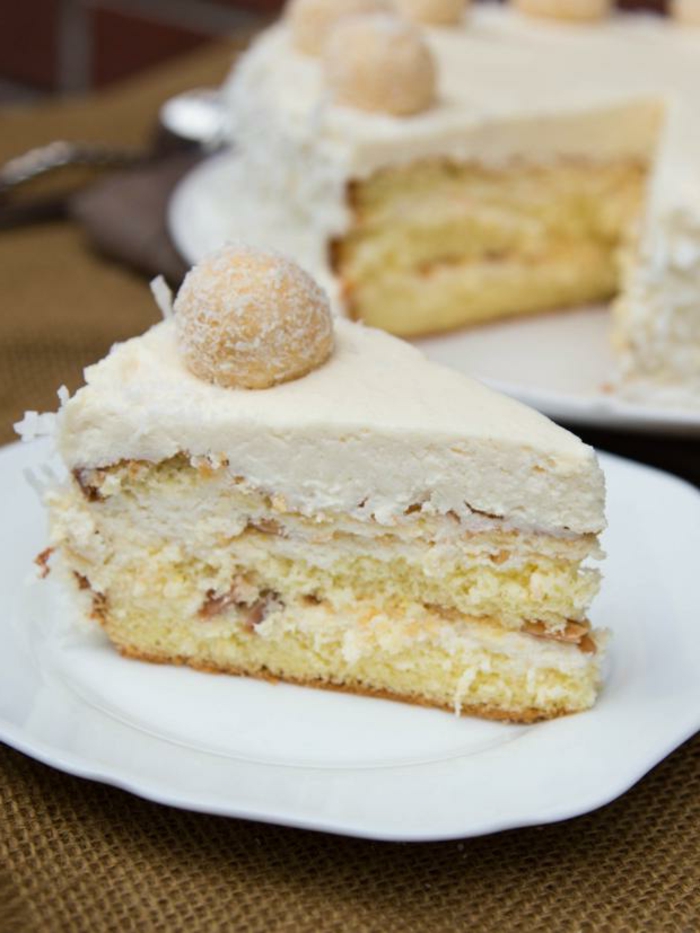ein Stück Kuchen, beige Glasur von Nüssen, Kokosraspeln darin, Raffaello Torte