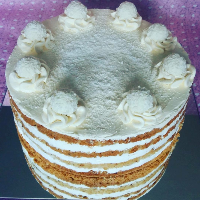 weiße Creme von der Torte, weiße Blumen und weiße Raffaello Pralinen, Kokos Torte