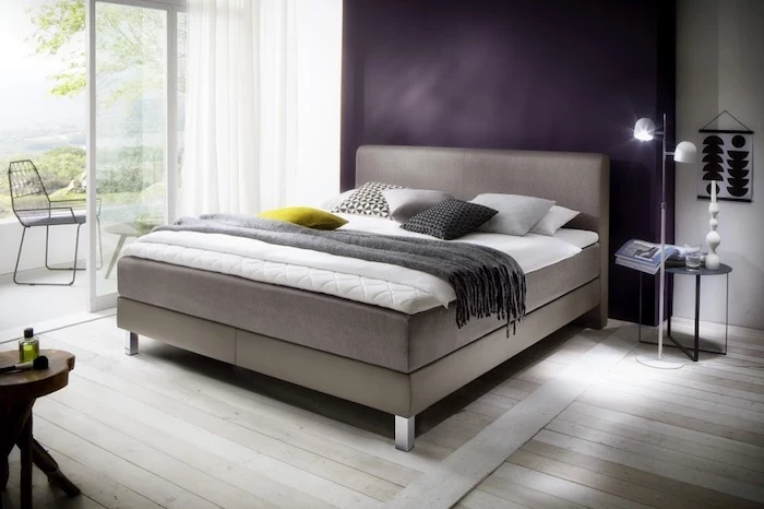 ein schlafzimmer mit violetter wand und einem boxspringbett