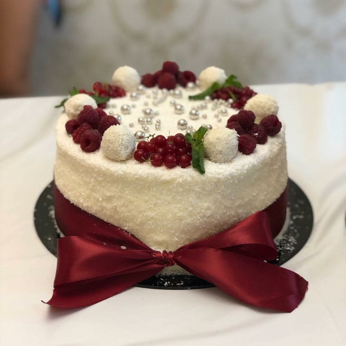 eine Mini Torte, die als echter Kunstobjekt aussieht, Raffaello Kuchen mit roter Schleife