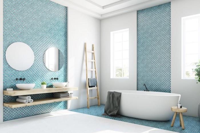 weiße kleine freistehende badewanne in einem blauen badezimmer mit blauen badezimmer fliesen und spiegeln und einem weißen waschbecken, badezimmer modern gestalten