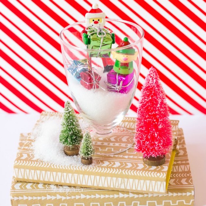 Künstlicher Schnee und kleine Weihnachtsfiguren in Glas füllen, bunte Weihnachtsbäume 