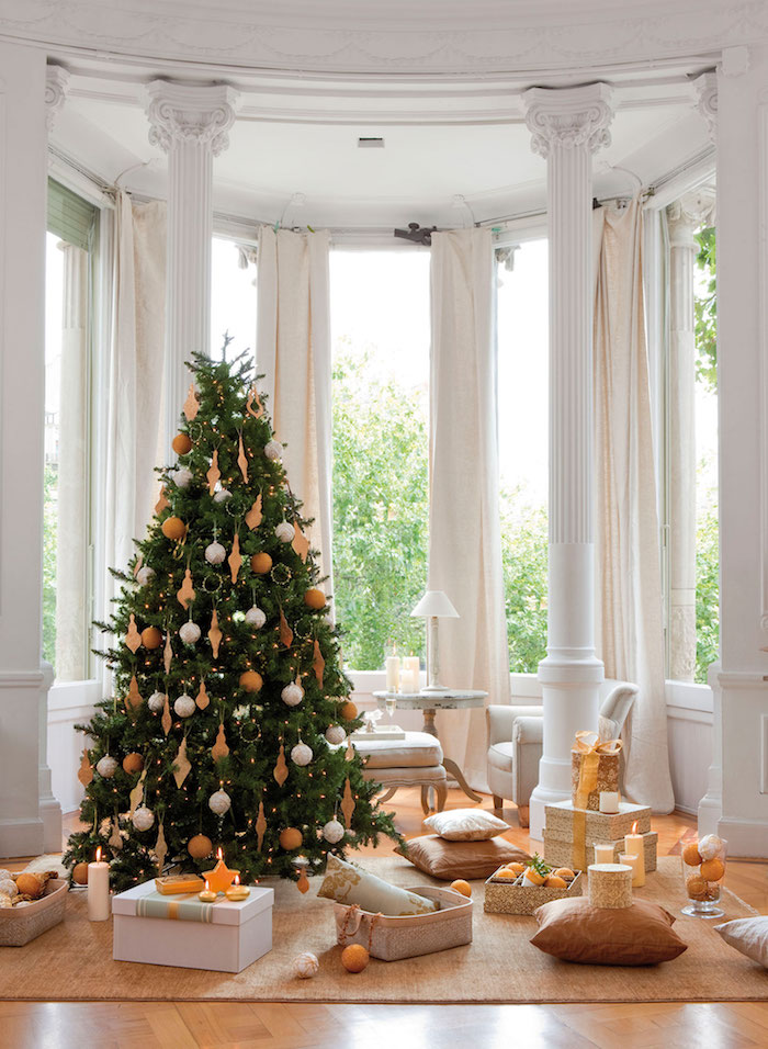 Weihnachtsbaum mit weißen und goldenen Christbaumkugeln, Dekokissen und Geschenkschachteln am Boden 