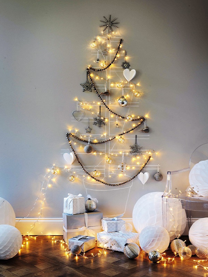 Weihnachtsbaum mit weißer Farbe an die Wand zeichnen, Lichterkette und Anhänger befestigen, Geschenke am Boden 