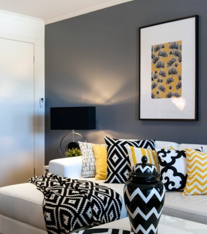 graue Wandfarbe, Wohnzimmer in Grau Weiß, gelbe Kissen und schwarz weiße Kissen mit verschiedenen Motiven