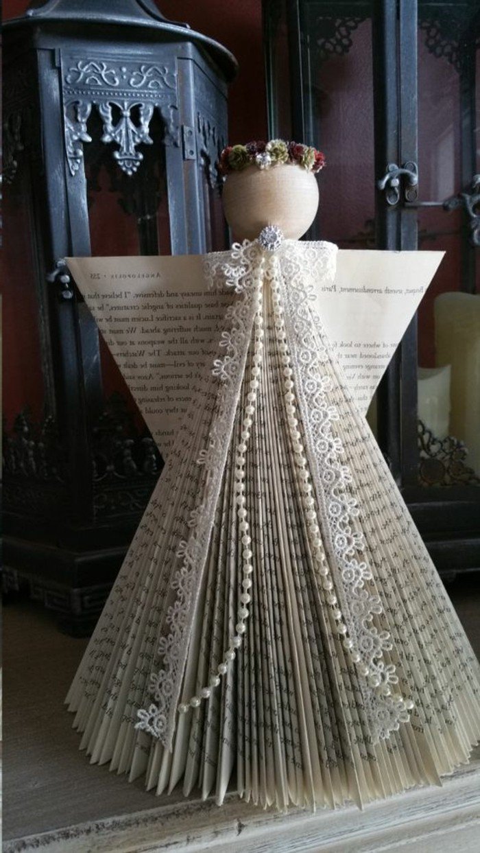 ein weißer Engel mit Spitzen und Perlen geschmückt, ein Kopf aus Holz, Buchseiten falten