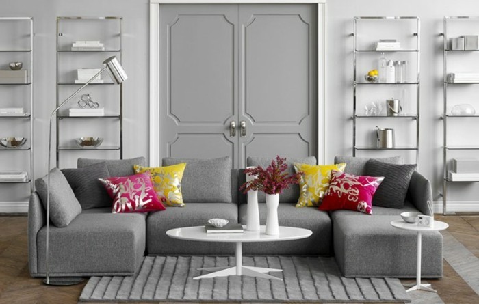 ein graues Sofa mit Kissen in rosa und gelber Farbe, ein kleiner runder weißer Tisch, Welche Farbe passt zu Grau