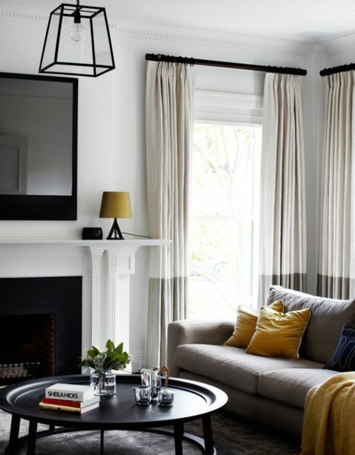 Wohnzimmer streichen Grau Weiß, weiße Vorhänge, ein Spiegel über dem Kamin, ein runder Tisch