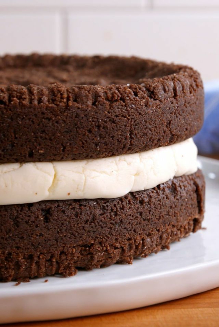 zwei Schokoladenböden, weiße Creme in der Mitte, ein großer Oreo Keks, Oreo Torte mit Milchcreme