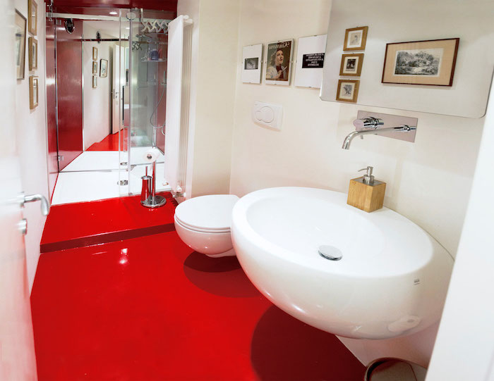 badezimmer mit einem roten boden und einem weißen waschbecken und weißen wänden mit bildern
