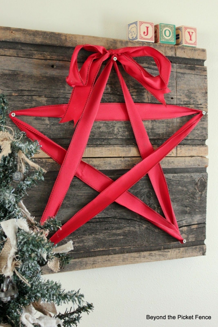 ein roter Stern aus einer Schleife, viele Nagel auf einem Brett, Bastelideen Weihnachten, neben Weihnachtsbaum