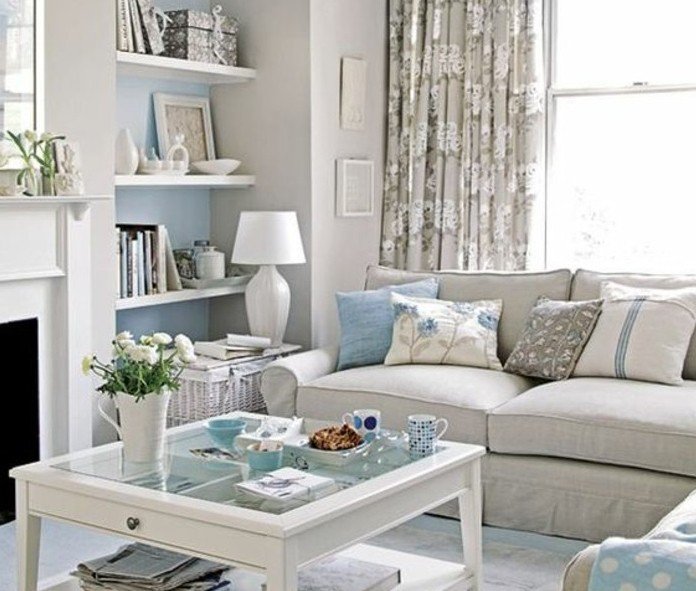 ein gläserner Tisch in weißer Farbe, ein graues Sofa, hellblaue Kissen, Wohnzimmer Ideen Weiß Grau
