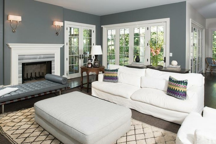 ein weißes Sofa mit zwei bunten Kissen, brauner Teppich, ein Kamin mit zwei Lampen darüber, Wohnzimmer Ideen Weiß Grau
