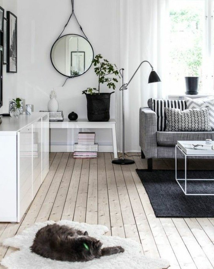 ein schwarzer Teppich, ein graues Sofa, Laminatboden, ein runder Spiegel, Wohnzimmer Ideen Weiß Grau