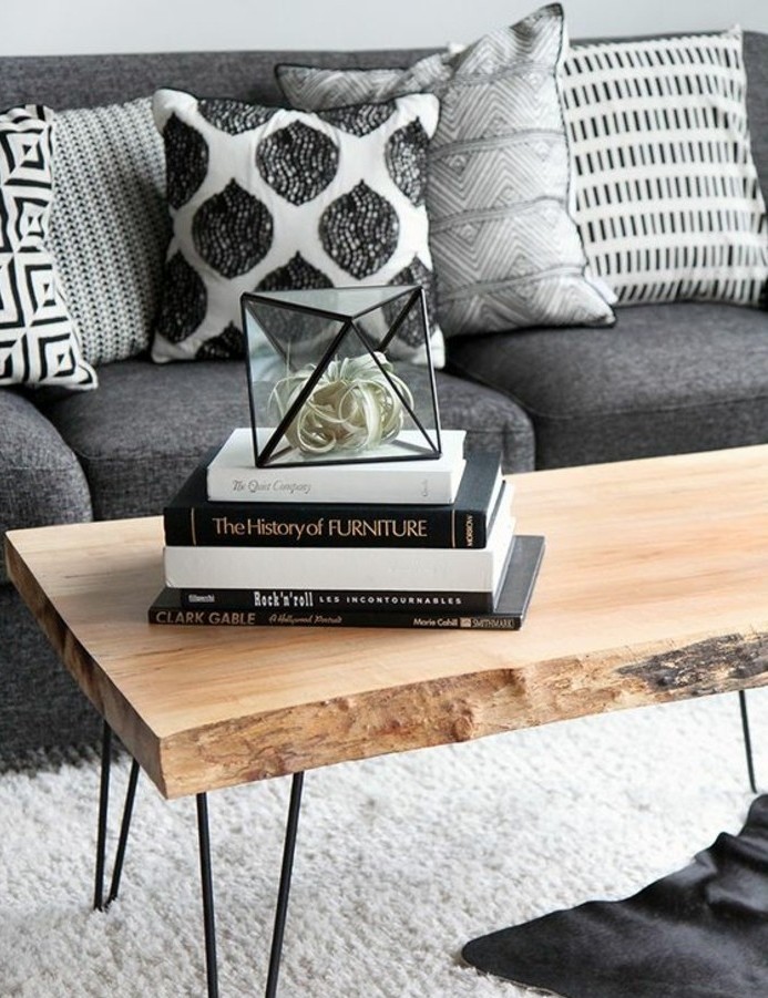ein graues Sofa, schwarz weiße Kissen, Wohnzimmer Grau Weiß, weißer Teppich, darüber Tisch aus Holz