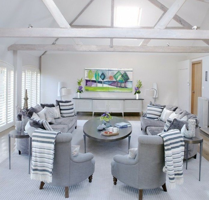 graue Sessel und graue Sofas, ein grauer Tisch und ein buntes Bild, eine Dachwohnung mit weißer Wandfarbe, Wohnzimmer Grau Weiß