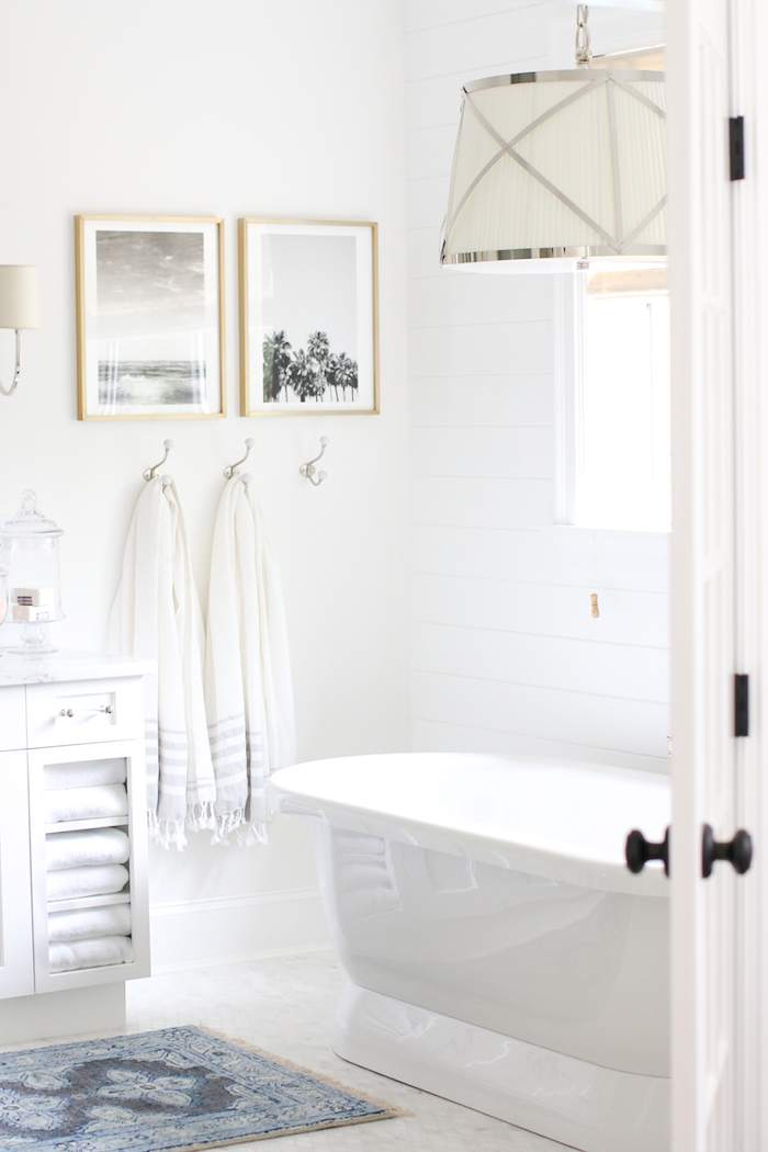 kleines weißes badezimmer mit einer weißen freistehenden badewanne und weißen tüchern, weiße badezimmer bilder, kleine madezimmer bilder