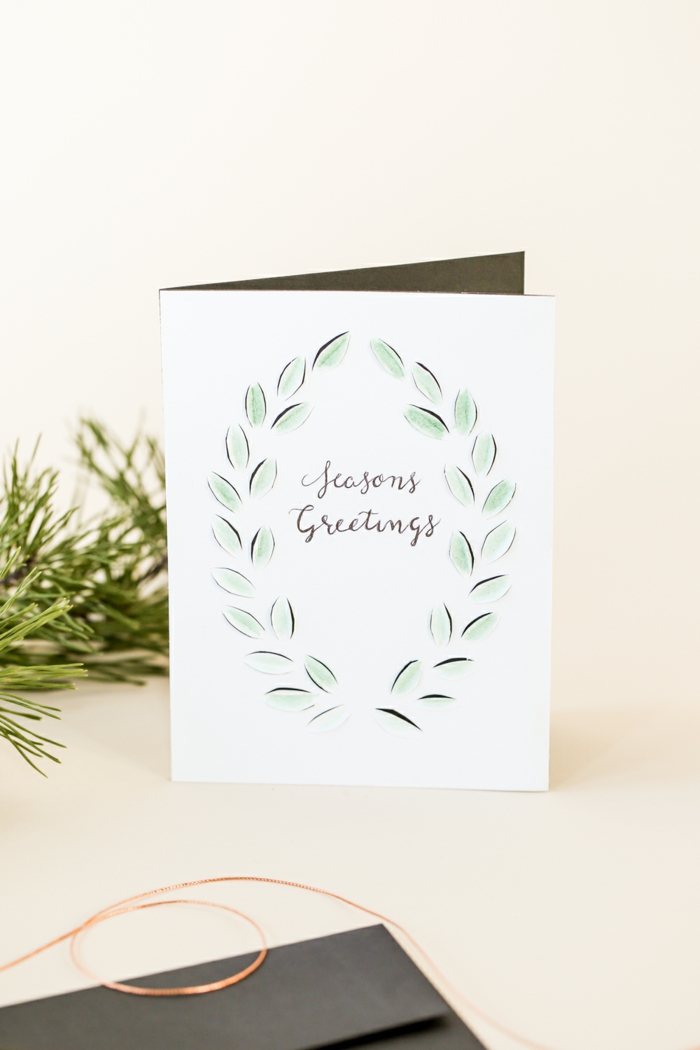 ein Kranz aus zarten grünen Blätter ist auf diesem Weihnachtskarten Design gezeichnet