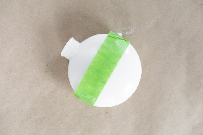 Weihnachtskugeln basteln, eine weiße Kugel als Vorlage mit grünem Tesafilm beklebt, damit die Hälfte nicht gefärbt wird