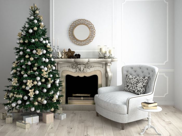 Weihnachtsbaum schmücken, mit weißen Weihnachtskugeln und goldenen Glöckchen, weißer Sessel, Bücher und Tasse Kaffee auf dem Couchtisch 