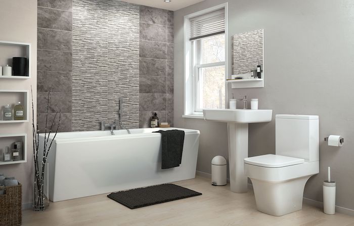 weiße freistehende badewanne und schwarze tücher und ein schwarzer teppch, badezimmer mit grauen wänden und mit kleinem fenster