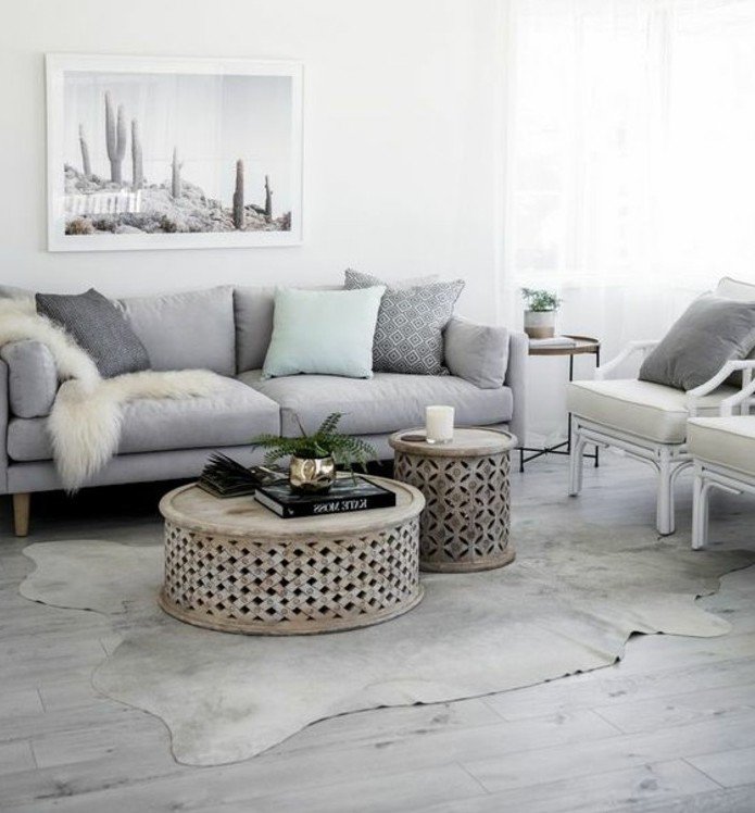ein graues Bild, graues Sofa, ein weißer Teppich, runde Couchtische, ein schönes Wandbild