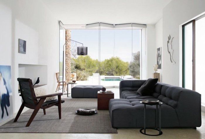 ein schwarzes Sofa, ein grauer Teppich, ein Glaswand, Wohnzimmer gestalten Weiß Grau