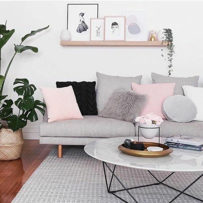 eine Leistne aus Holz voller Bilder mit bunten Rahmen, graues Sofa mit rosa Kissen, Wohnzimmer gestalten Grau Weiß