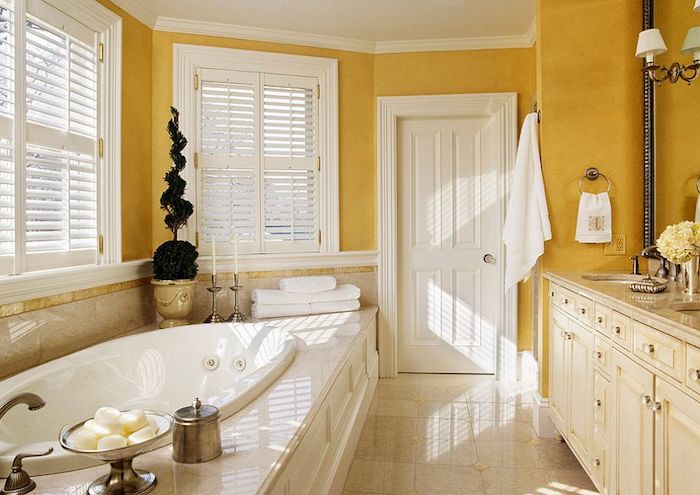 badezimmer gelb, ein badezimmer mit gelben wänden und weißen fenstern aus holz und eine große weiße badewanne und eine weiße tür