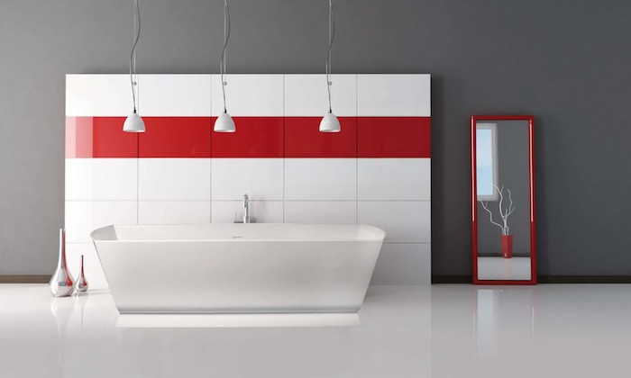weißer boden und eine wand aus großen weißen und roten badezimmer fliesen, weiße freistehende badewanne und ein großer spiegel 