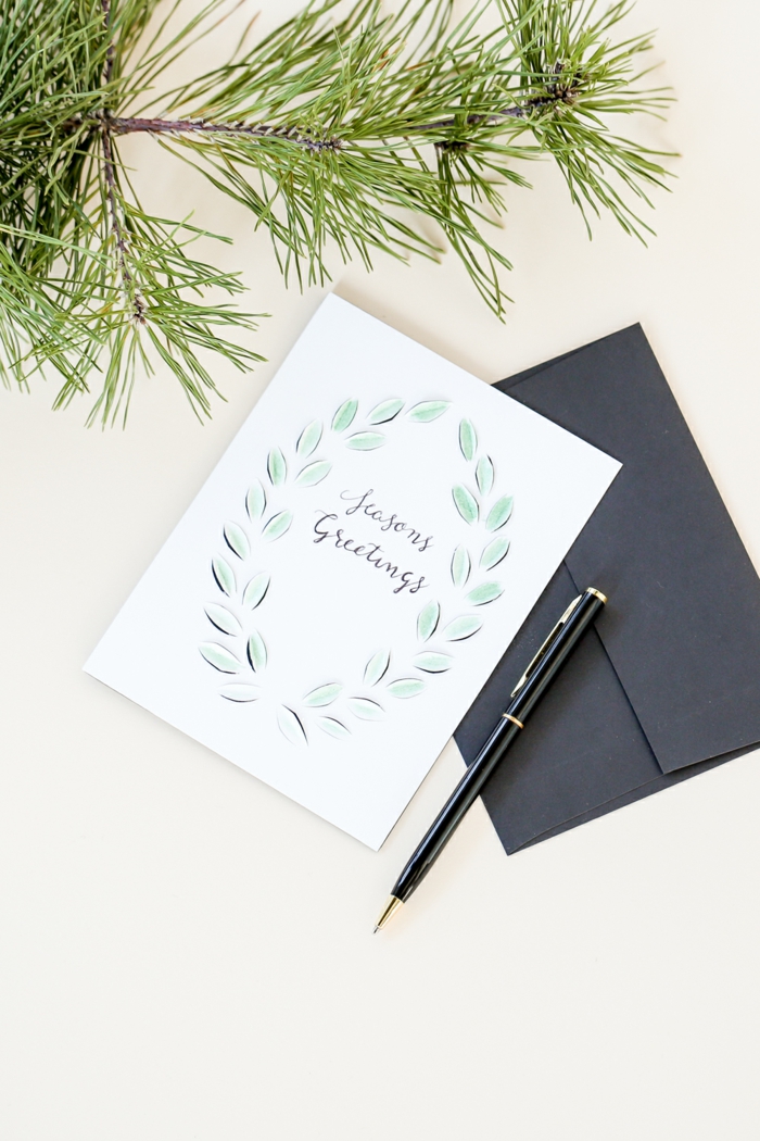 Tannenzweigen, weiße Karte, schwarzer Briefumschlag, Aufschrift mit Kugelschreiber, Weihnachtskarten Design