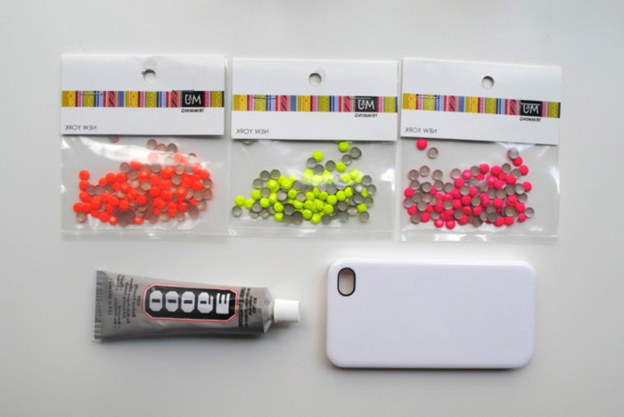 drei Päckchen mit Glasperlen, Klebstoff und eine Handyhülle, Materialien für Handyhülle designen