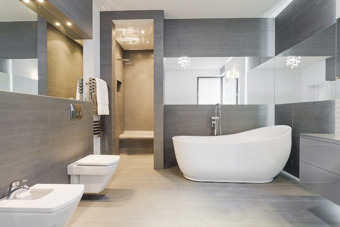 weißes waschbecken im badezimmer mit grauen wänden und spiegeln, eine weiße freistehende badewanne 