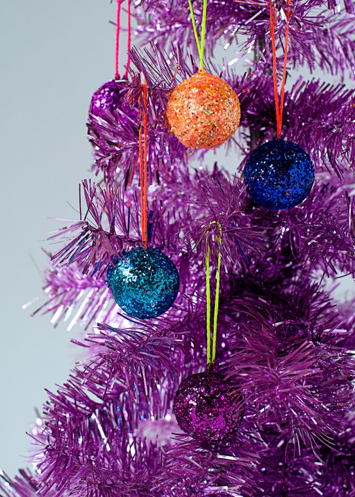 blaue Kugeln, orange Kugel und lila Kugel, Weihnachtskugeln bemalen und auf lila künstlichen Christbaum hängen