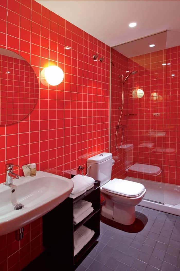 rotes badezimmer mit roten wänden und ein weißes waschbecken und kleiner spiegel und eine badezimmer lampe, badezimmer mit einer dusche