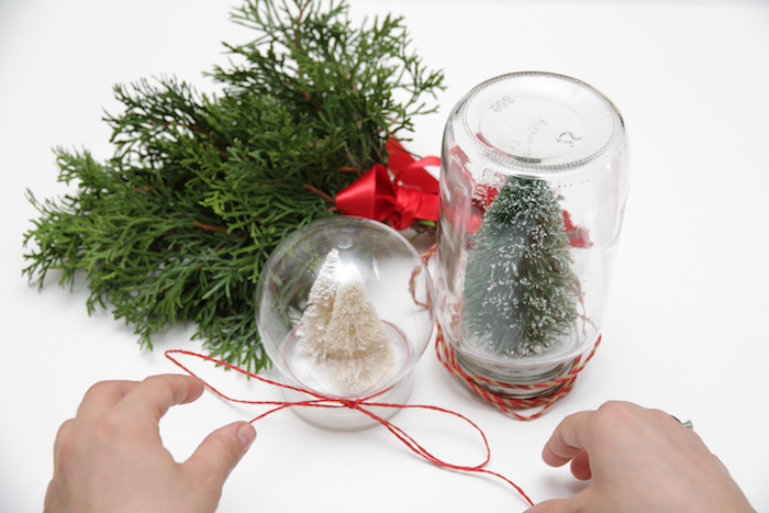 Zwei selbstgemachte Schneekugeln mit Weihnachtsbäumen darin, Faden um das Glas wickeln 
