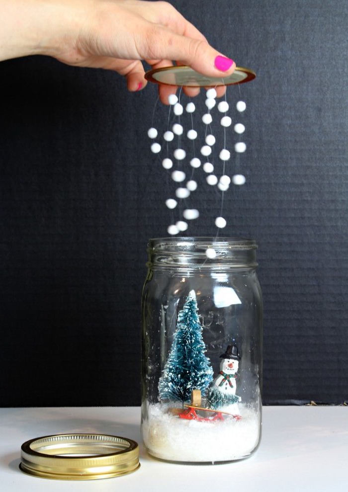 Schneekugel selber basteln, kleine weiße Pompons als Schneeflocken, Schneemann und Weihnachtsbaum im Glas 