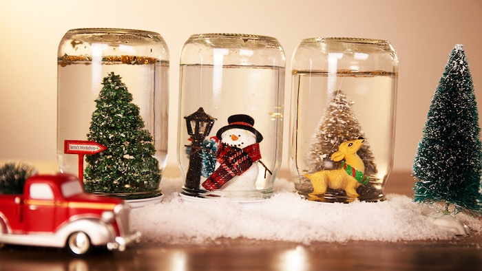 Drei selbstgemachte Schneekugeln mit Weihnachtsbaum, Schneemann und Rentier, rotes Spielzeugauto 