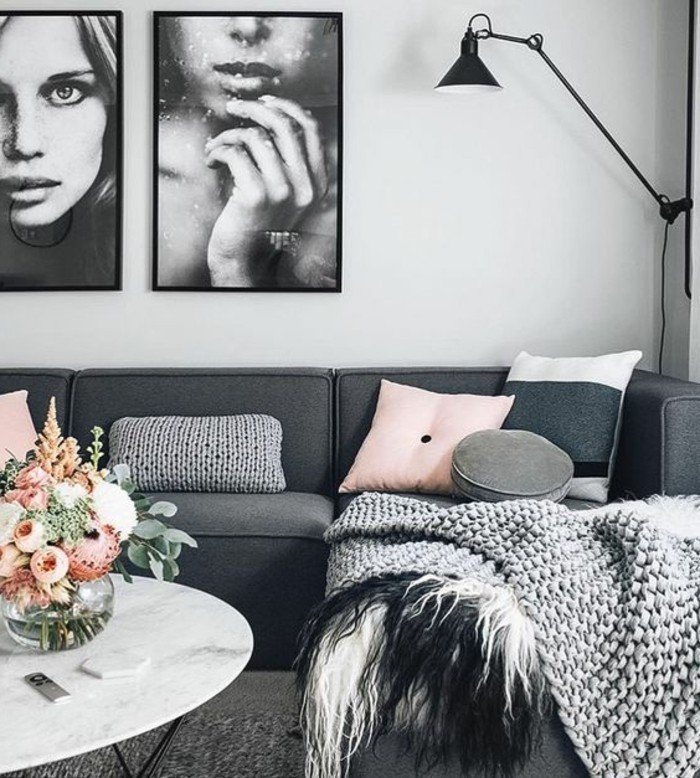 ein graues Sofa, rosa Kissen, weiße Wandfarbe, ein weißer runder Couchtisch, Wohnzimmer Weiß Grau