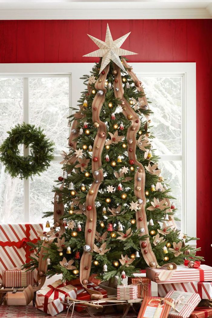 Großer Weihnachtsbaum geschmückt mit bunten Christbaumkugeln und Schleifen, schön verpackte Weihnachtsgeschenke unter dem Baum 