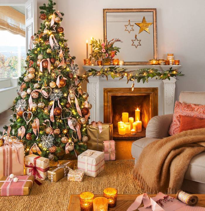 Weihnachtsbaum geschmückt mit goldenen Weihnachtskugeln und Schleifen, Kerzen im Kamin, viele Geschenke unter dem Baum, Dekokissen und kuschelige Decke auf dem Sofa, Teelichter auf dem Couchtisch und auf dem Kamin 