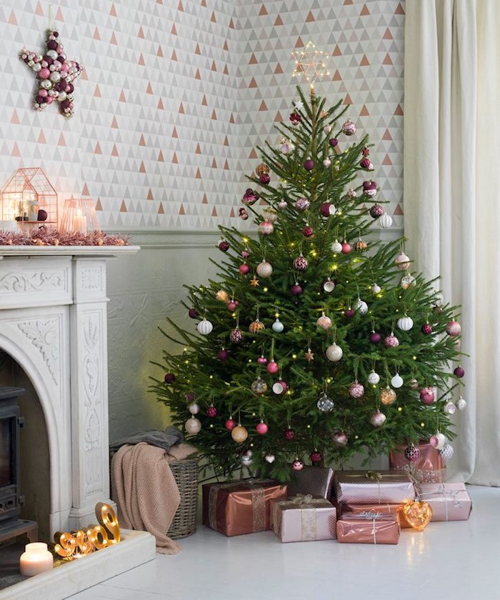 Echter Weihnachtsbaum geschmückt mit bunten Christbaumkugeln und Lichterkette, schön verpackte Geschenke unter dem Baum 
