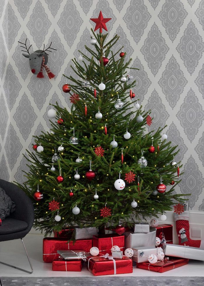 Echter Weihnachtsbaum geschmückt mit roten und weißen Christbaumkugeln, viele Geschenke unter dem Baum 